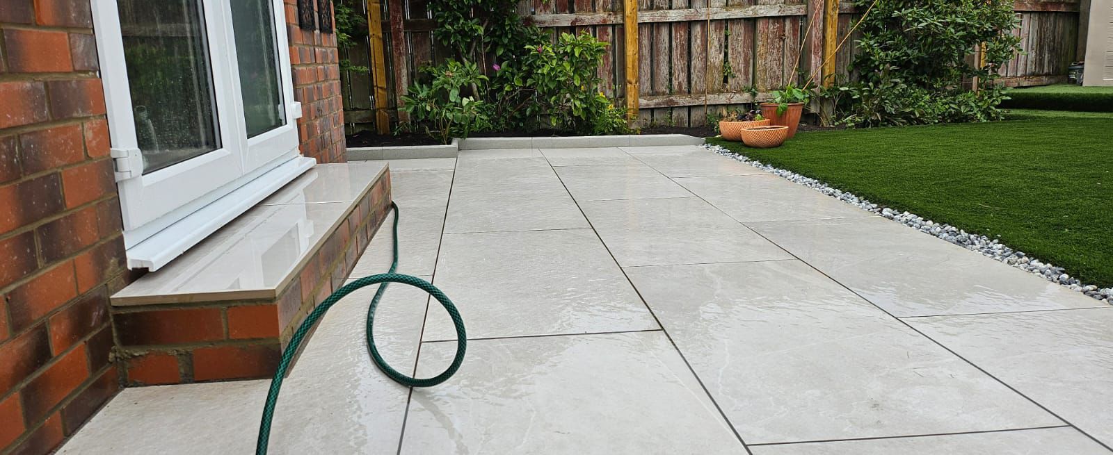 Paved garden terrace beside a lawn and house
