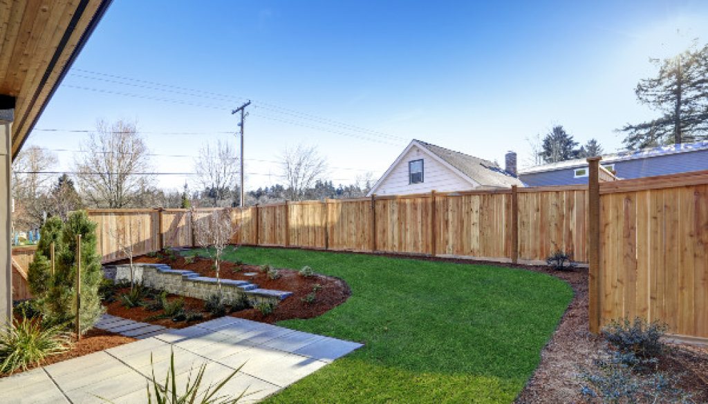 Garden with a paved terrace, lawn and timber fencing