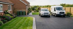 A smooth, freshly laid black tarmac driveway in front of a typical North East semi-detached home on a bright July day