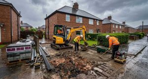 Workers excavating a driveway at a North East home during a light summer rain shower