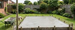 Newly poured concrete base with timber shuttering in a UK back garden