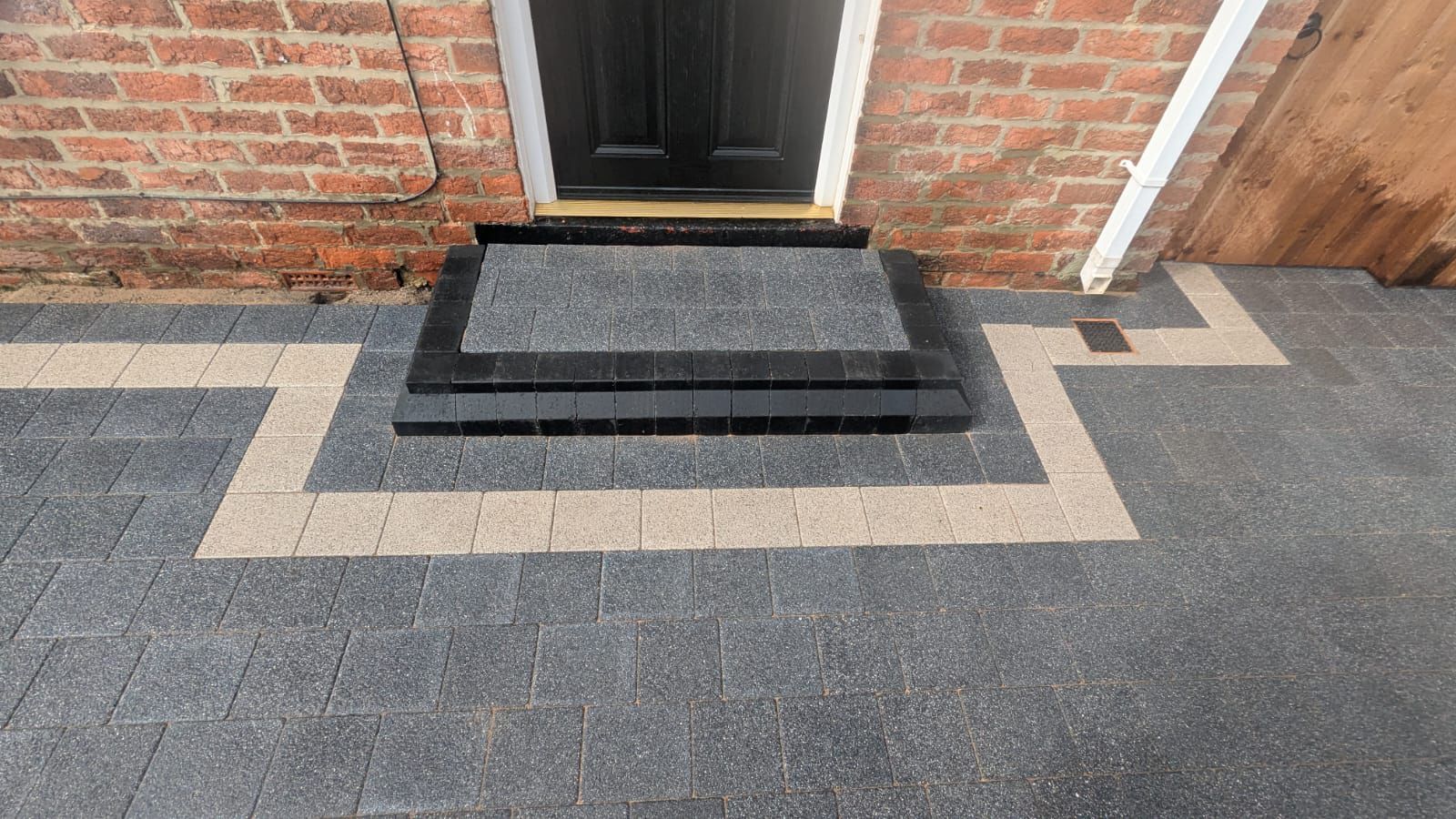 Grey block paving and a raised doorstep with contrasting pale borders