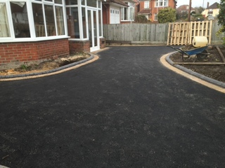 Curved tarmac driveway beside a brick home with contrasting edging