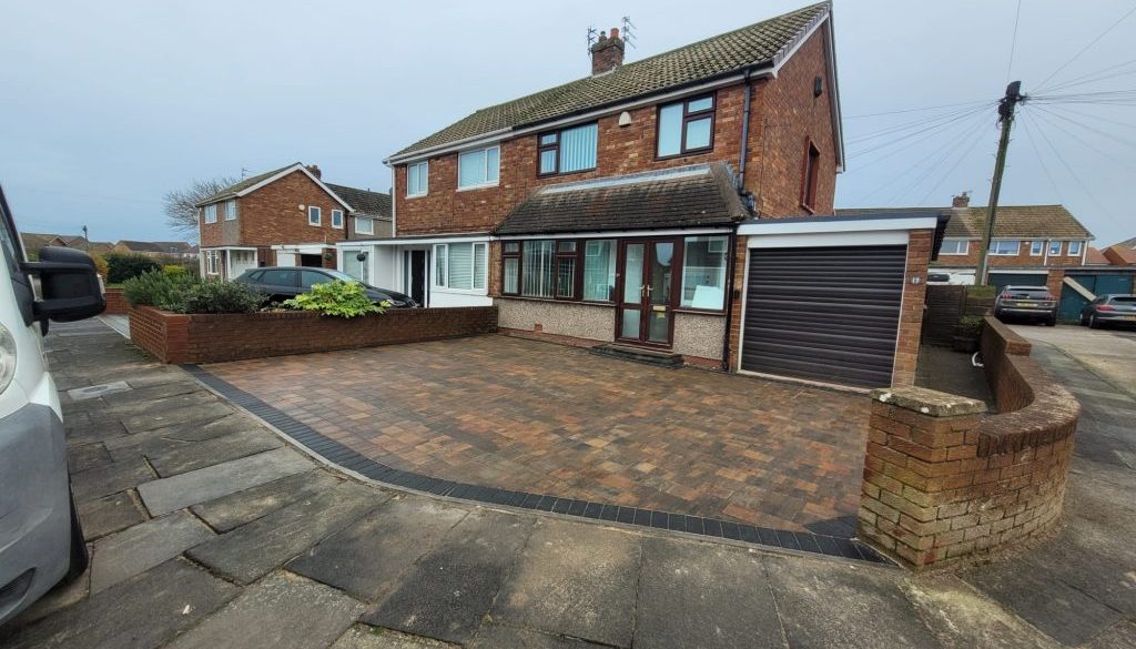 Completed block paved driveway beside a brick house