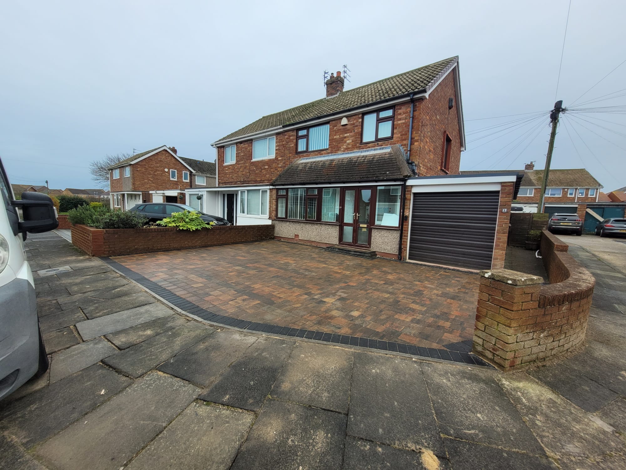 Completed block paved driveway beside a brick house