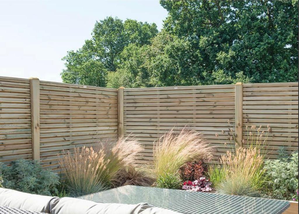 Horizontal slatted timber fencing behind ornamental garden planting