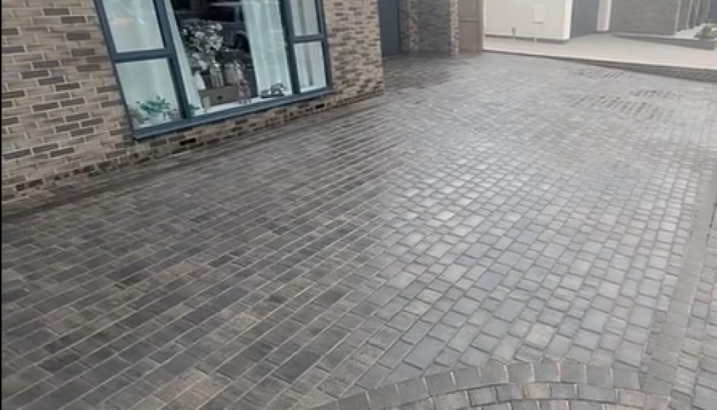 Block paved driveway beside a stone-built home