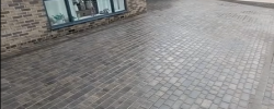 Block paved driveway beside a stone-built home