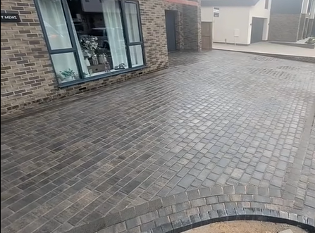 Block paving driveway with curved edging outside a brick home