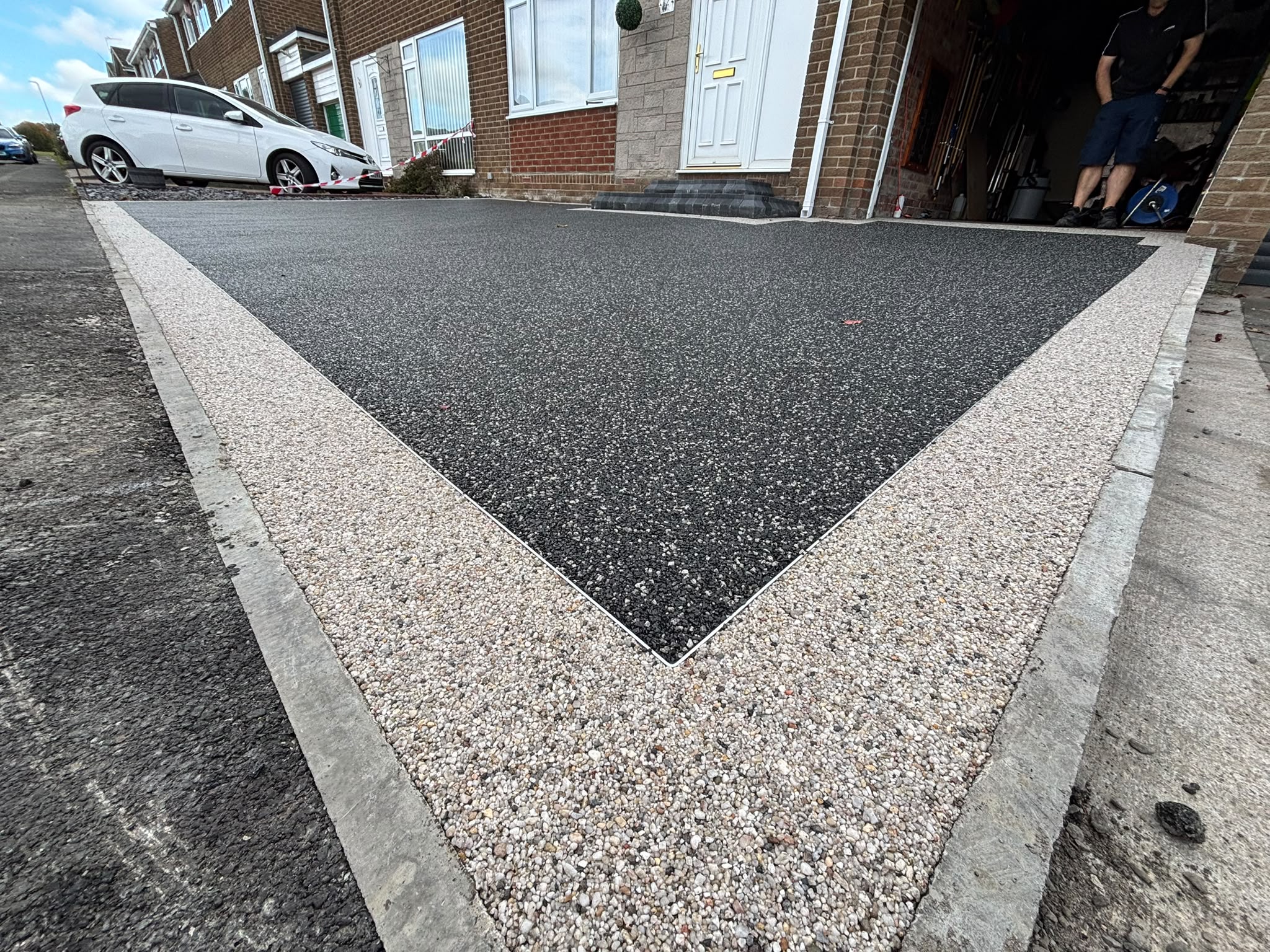 Charcoal resin driveway framed by pale stone borders